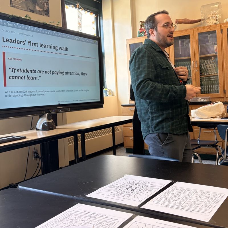 Dan presenting at researchED next to a screen titled Leaders' first learning walk.